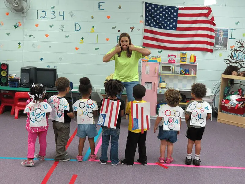 A group of children standing in front of an american flag.