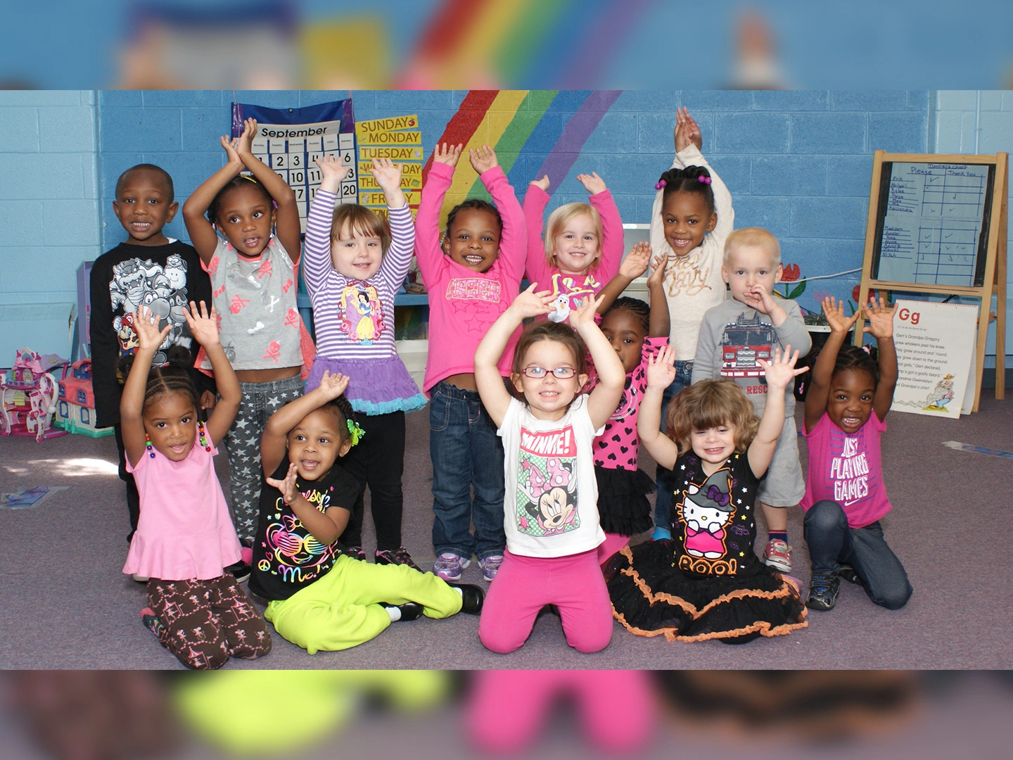 A group of children in pink shirts and black pants.