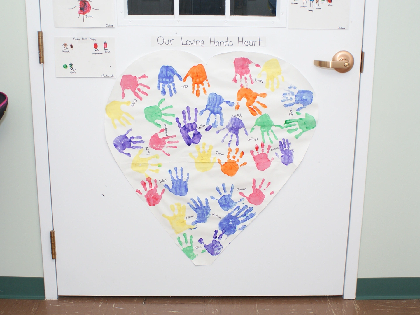 A heart shaped door with many hands painted on it.