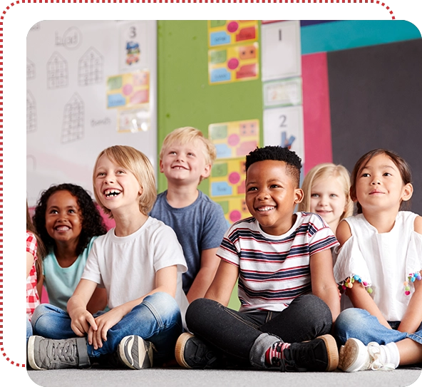 A group of children sitting in front of a wall.