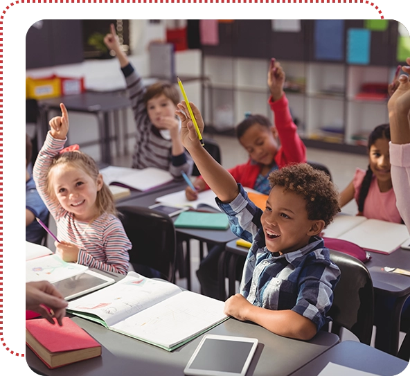 A group of children sitting at desks in front of books.