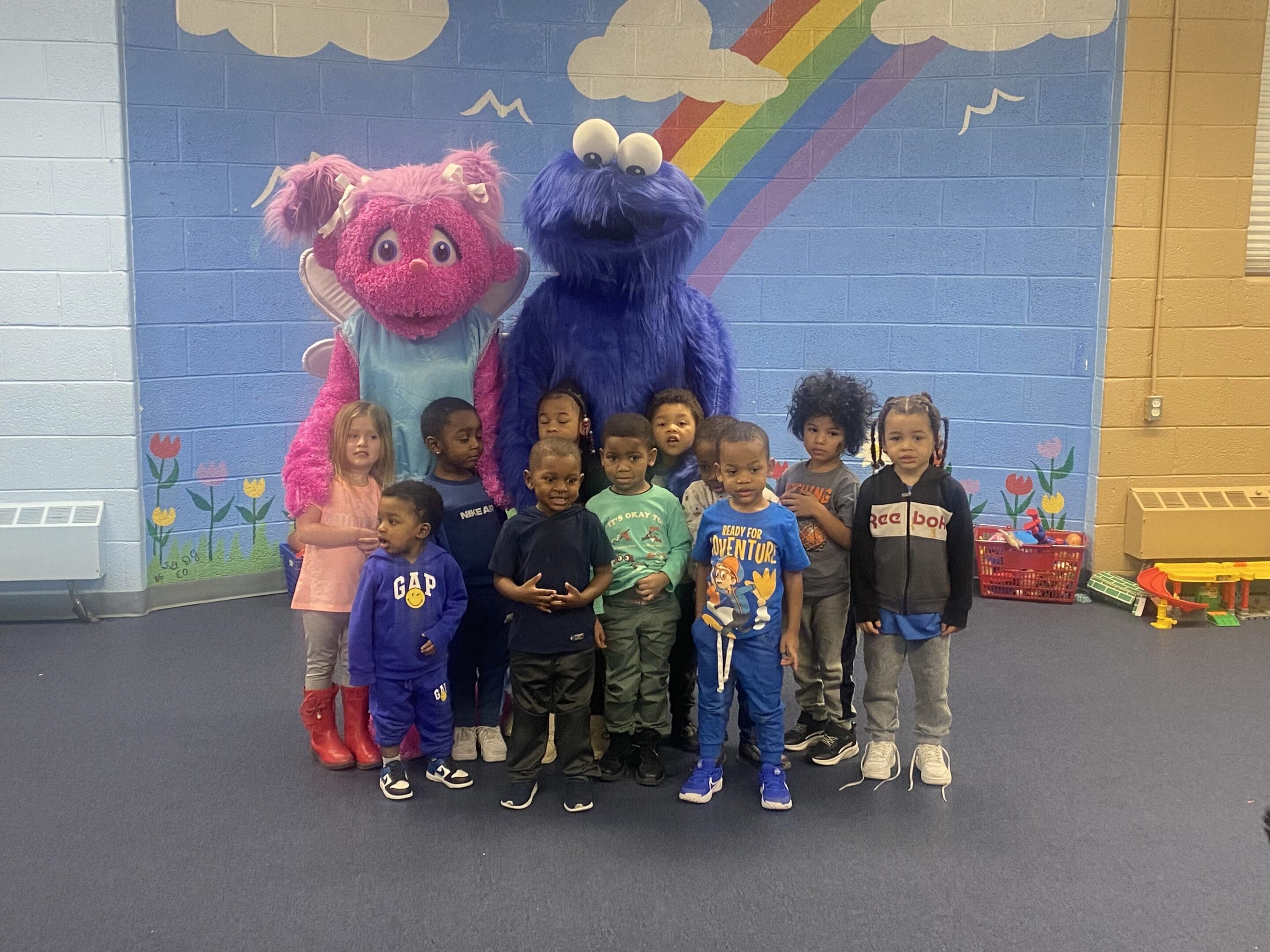 A group of children posing with sesame street characters.