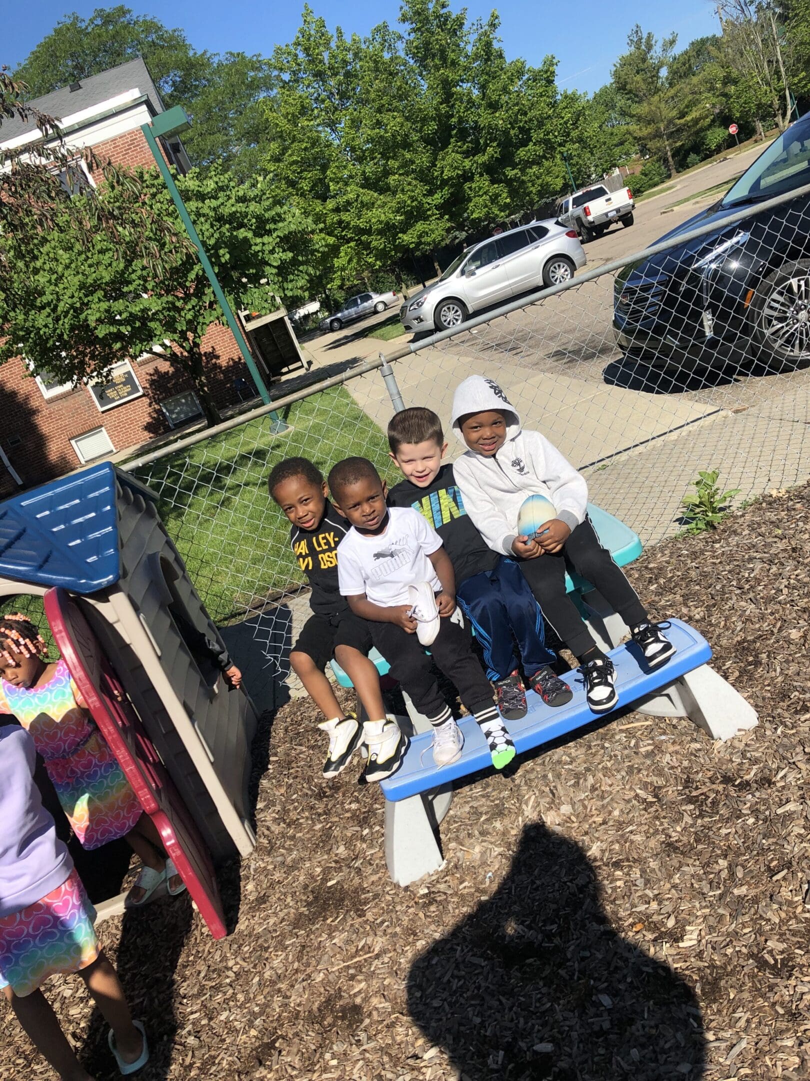 A group of kids sitting on top of a blue bench.